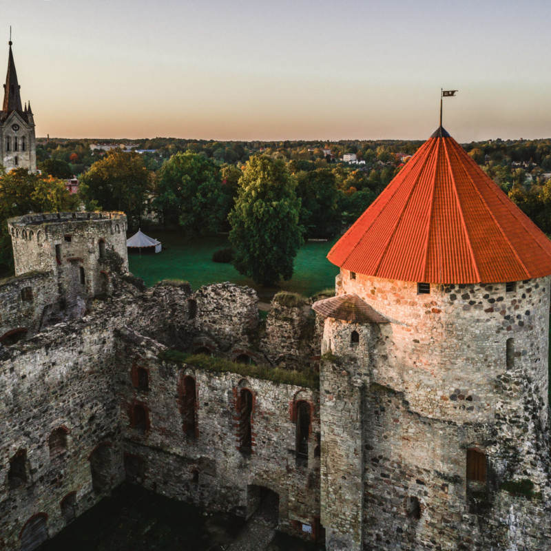 Cēsis: Die Deutschordensburg mit der St.-Johannis-Basilika im Hintergrund