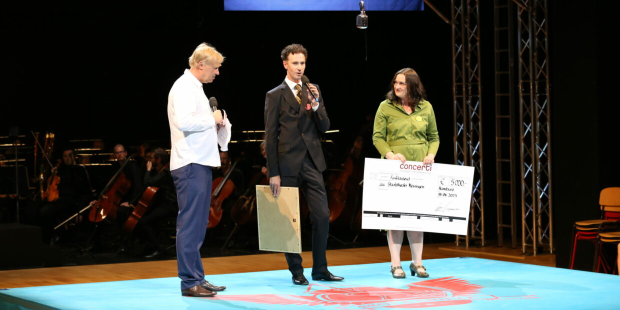 Gregor Burgenmeister, Herausgeber von concerti, und Redaktionsleiterin Susanne Bánhidai überreichen Urkunde und Preisgeld an den Intendanten Jens Neundorff von Enzberg.